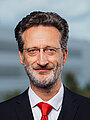 Rektor Prof. Dr.-Ing. Jean-Alexander Müller  Portrait einer lächelnden Person vor einem Hochschulgebäude